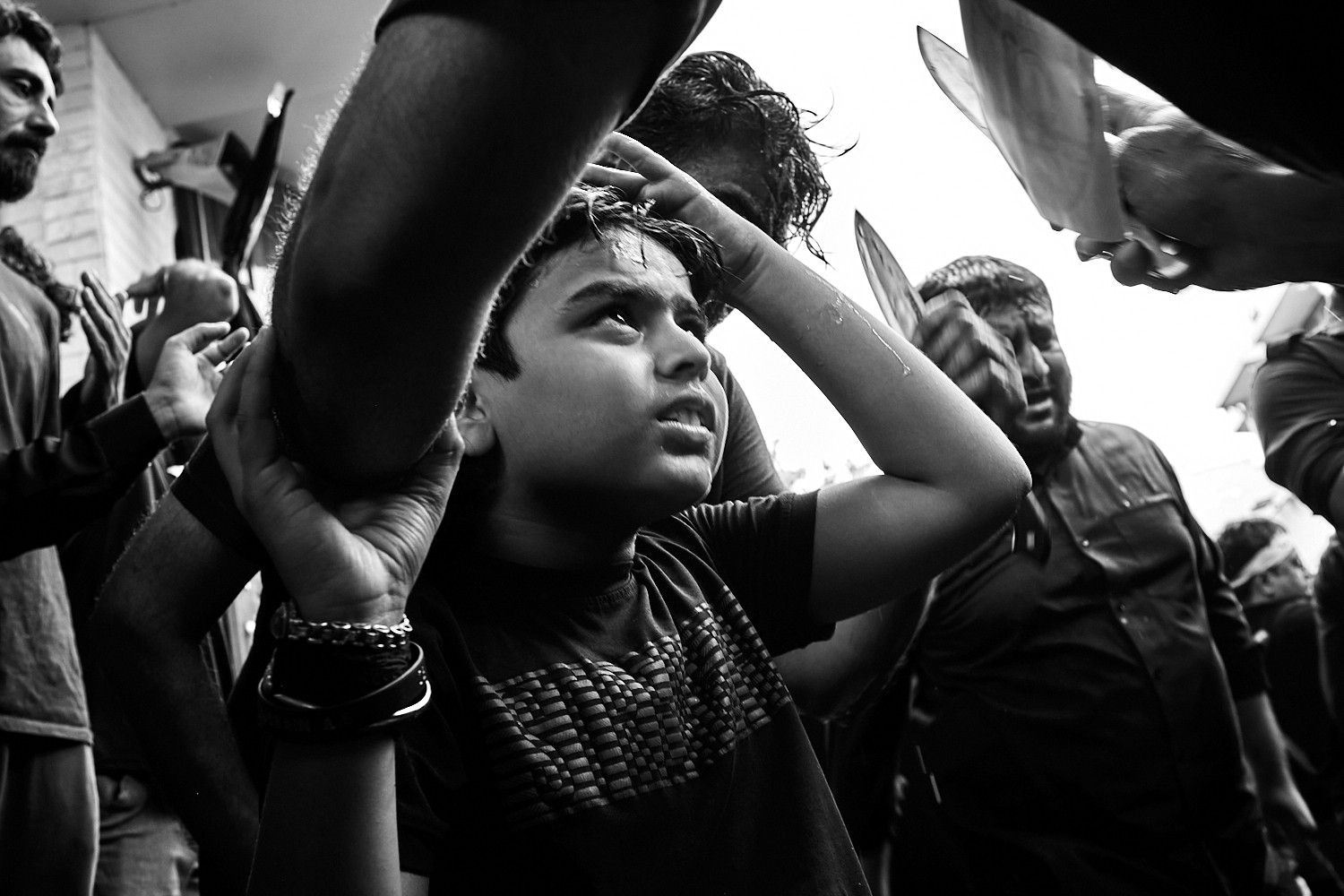 A young boy reacts as he prepares to receive a cut on his forehead with a knife. Ahmedabad, India. 2024
